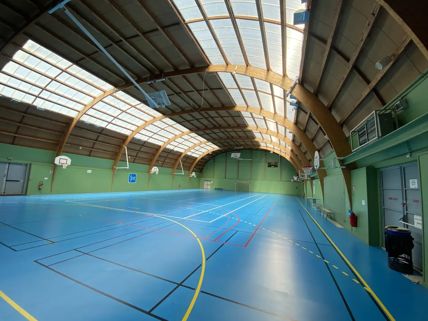 Sol sportif PVC bleu en gymnase avec marquage multisport basket volley badminton