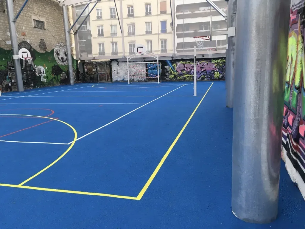 Sol sportif en résine synthétique bleue avec marquage jaune pour terrain de basket 3x3 à Paris