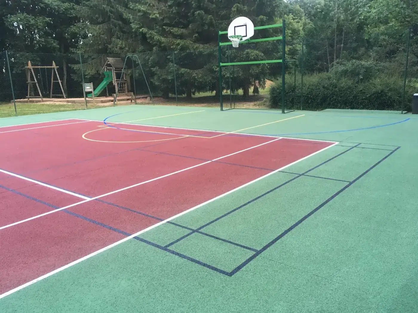 Terrain multisport extérieur en résine rouge et verte avec marquage multi-activités